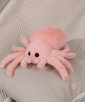 Super Soft Pink Spider Plush Toy For Kids And Adults on a pillow, 9.8 inch, fluffy and cuddly stuffed animal for playtime and decor.