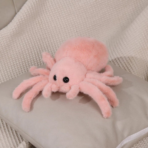Super Soft Pink Spider Plush Toy For Kids And Adults on a pillow, 9.8 inch, fluffy and cuddly stuffed animal for playtime and decor.