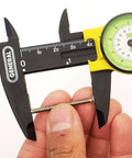 Close-up of plastic dial caliper measuring a screw, 0 to 6 inch range, fiberglass body for precise measurements, ideal for workshops.