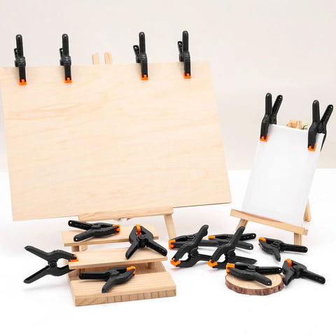 24 Pack 3.5 Inch Plastic Spring Clamps Black Heavy Duty Clips, shown holding wood and canvas, used for crafts and photography.