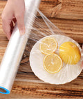Hands using stretch film to cover lemon slices on a plate, showcasing 24 Pack Stretch Wrap Dispenser Hand Savers For Moving And Shipping Easy Grip Plastic Puller Fits 3 Inch Core Pallet Wrapping Durable Blue And Orange Handles Bulk Replacement For Packing Film And Pallets.