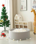 Ball Pit Balls Plastic Playballs for Baby Toddlers Kids Boys Girls Playhouse Decor Play Pool Fun Phthalate-Free BPA-Free Bath Toy White Beige Transparent,100 Balls in gray ball pit beside Christmas tree and toy giraffe in nursery room.