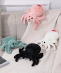 Assorted colored spider plush toys on a couch, including the White Spider Plush Stuffed Animal Toy for Kids with Ultra Soft 9.8 Inch Jumping Spider Plushie.