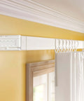 Installed white drapery rod with adjustable brackets for wide pocket rods, seen in a living room setting.