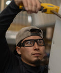 Worker wearing Brazeau Polarized Safety Glasses With 99.9 Percent UV Protection And ANSI Z87, using a tool indoors.