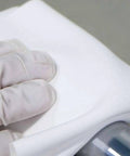 Gloved hand using Ultrasonic Sealed Edge Cleanroom Wiper For Sensitive Surfaces 9 Inch By 9 Inch Polyester Knit on a surface