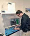 Technician working with a computer under a 30 Inch Wide Portable Laminar Flow Hood Lab Grade For Medical And Laboratory Use with Positive Pressure