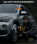 Man using Portable Tire Inflator With Dual Power Motors And Bright LED Light 150 PSI 12V DC Or 110V AC on car tire in dim environment