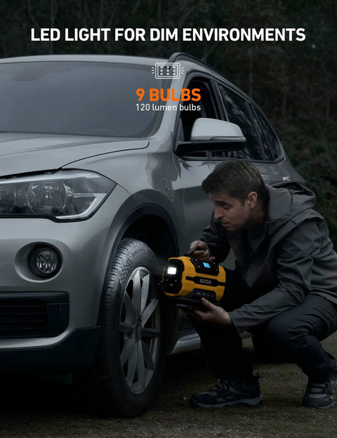 Man using Portable Tire Inflator With Dual Power Motors And Bright LED Light 150 PSI 12V DC Or 110V AC on car tire in dim environment
