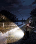Rechargeable 100W LED Work Light illuminating a nighttime fishing scene by a lake, showing its Beast Mode Brightness and stand.
