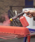 Person using HotCoat PCS-250 Powder Coating System with red powder on a metal part, highlighting dual voltage gun action.