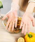Person wearing a Powder Free Vinyl Glove 4.3 Mil Clear Latex Free for food service, preparing vegetables in a kitchen setting.