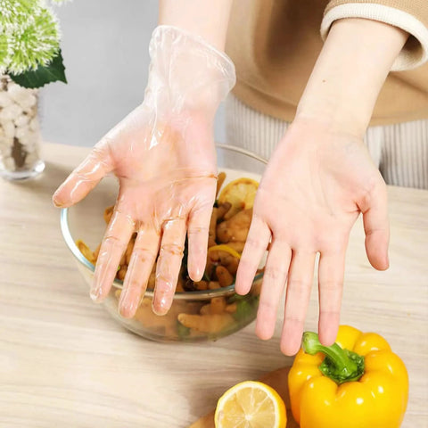 Person wearing a Powder Free Vinyl Glove 4.3 Mil Clear Latex Free for food service, preparing vegetables in a kitchen setting.