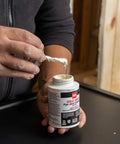 Person holding Pro Grade Pipe Joint Compound with PTFE brush, 8 oz, white non-hardening paste for threaded joints, Oatey 31231