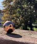 Unique Metals Pure Copper Sphere 1-1/8" for healing, decorative use, grounding, alchemical magic on wooden surface outdoors