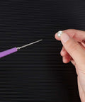 Person holding bead next to Purple-handled tool from 10 Piece Bead Reamer Set For Jewelry Making And Beading Diamond Tipped Reamers For Enlarging Holes In Glass Plastic Metal Wood Removing Burrs And Smoothing Edges Perfect For DIY Crafting Mudder on striped background.