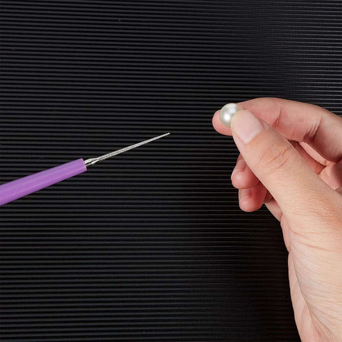 Person holding bead next to Purple-handled tool from 10 Piece Bead Reamer Set For Jewelry Making And Beading Diamond Tipped Reamers For Enlarging Holes In Glass Plastic Metal Wood Removing Burrs And Smoothing Edges Perfect For DIY Crafting Mudder on striped background.