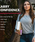 Woman holding books and compact police-strength pepper spray with quick release keychain for fast access outdoors