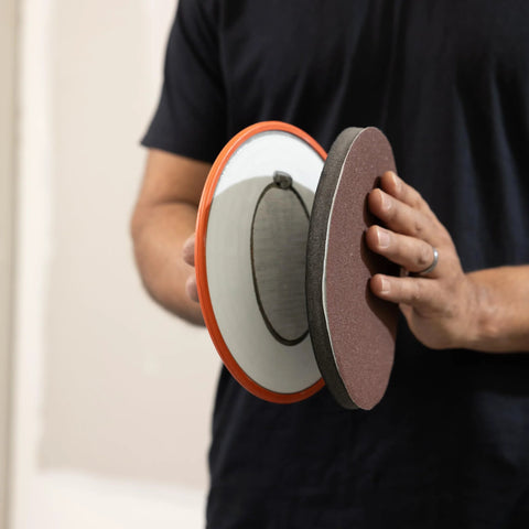 Person holding Radius360 Round Sanding Tool with Interchangeable Center Hub 9 Inch, showing front and back sides.