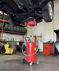 Lincoln 3601 Pneumatic 18 Gallon Pressurized Fluid Drain and Evacuation Tank in use under a vehicle in a garage.