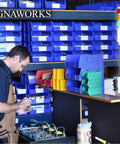 Workshop with man working on electronics, Red LED Andon Light Tower With One Stack Off On Switch 8 Foot Industrial Power Cord Plug And Play Ready 3 Prong OSHA Compliant Plug Indoor Rated Assembled In USA High Brightness Visual Indicator For Production Line visible on desk.