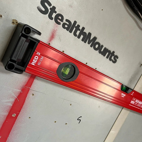 Red level mounted on wall with yellow universal level holder 2 pack for secure storage.