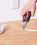 Using 10-In-1 Stainless Steel Multitool With Safety Lock And Red Nylon Sheath to cut wire on wooden floor
