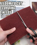 Hands cutting Six Pack Red Scuff Pads Very Fine Grade for Paint Prep and Finishing 8 x 5 Inches with scissors