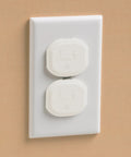 Close-up of white electrical outlet with two removable, reusable covers sealing live sockets to keep curious hands safe