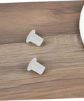 Two durable plastic side plugs for inline skate wheel bearings on a wooden surface, part of a 50 Piece Durable Plastic Side Plugs Replacement Spacers set.