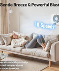Woman on sofa showing 8 Inch Through Wall Room To Room Fan With Remote 320 CFM Air Transfer Temperature Control Reversible Airflow 10 Speeds Quiet Exhaust Vent For Bedroom Laundry And Kitchen From Windigaga installed on wall