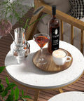 Round patio table with drinks, plant decor, and bottle on wood tray