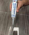 Clear RTV Silicone Adhesive Sealant 3 Oz Sensor Safe General Purpose Sealant For Inside Or Outside Use That Bonds Seals Repairs Glass Metal Plastic Vinyl Fabric Weather Stripping And More For Quick Fixes being applied to a surface.