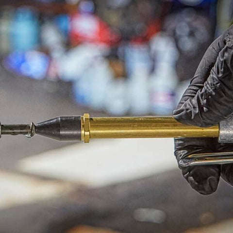 Lever Style Grip Air Blow Gun With Rubber Tip, close-up of brass nozzle, held in gloved hand, for industrial debris clearance