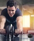 Man exercising with ab roller in gym, Anti Vibration Feet Pads For Gym Equipment 4 Pack Rubber Bumpers visible on floor