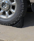 Durable Laminated Rubber Wheel Chock With Sturdy Metal Handle for Quick Safe Vehicle Blocking on a truck wheel on concrete surface.