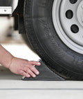 Hand placing Beefy Rubber Wheel Chock For Cars Trailers RVs And Utility Vehicles With Reinforced Grip Weather And Chemical Resistant 5x6x5 Inch under tire