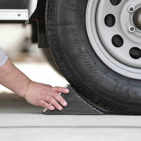Hand placing Beefy Rubber Wheel Chock For Cars Trailers RVs And Utility Vehicles With Reinforced Grip Weather And Chemical Resistant 5x6x5 Inch under tire