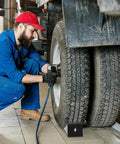 Mechanic working on truck with Rugged 2 Pack Solid Rubber Wheel Chocks for RVs, Campers, Trailers and Trucks under wheel