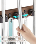 Hand using Rustic Wood Wall Mount Mop And Broom Organizer With 4 Slots And 4 Hooks For Closet Garage Laundry Kitchen Decor