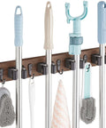 Rustic Wood Wall Mount Mop And Broom Organizer With 4 Slots And 4 Hooks holding cleaning tools in garage or kitchen setup