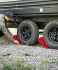 Man using Camper Leveler Block With Rubber Mat For RVs And Trailers, Precise Leveling From One Half Inch To Four Inches on gravel