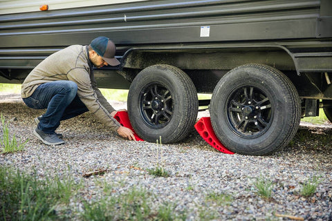 Man using Camper Leveler Block With Rubber Mat For RVs And Trailers, Precise Leveling From One Half Inch To Four Inches on gravel