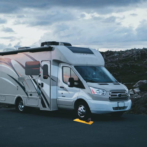 RV stabilized on road using Interlocking Camper Leveling Blocks Kit With Anti Slip Ramps 10 Pack Includes One Wheel Chock And Handy Carrying Bag For Travel Trailer And RV No Slip Rock Solid Stabilization On Uneven Ground