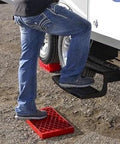 Heavy Duty RV Leveling Block Set 6 Pack With Free Step For Stable Parking with person using step next to RV tires.