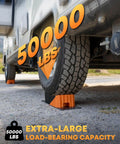 Heavy Duty RV Leveling Blocks Five Inch For Trailers Up To Fifty Thousand Pounds With Curved Camper Levelers Anti Slip Joint System Wheel Chocks Rubber Mats And Carry Bag Orange installed under RV wheel with 50,000 lbs capacity highlighted.