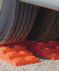 Interlocking RV Leveling Blocks 10 Pack With Nylon Storage Bag For Trailer Motorhome And Vanlife Up To 40,000 Lbs Capacity Orange Made In USA By Tri-Lynx Lynx Levelers under a vehicle tire on gravel