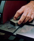 Close-up of hand using Sanding Block 3 Pack With Fine Medium Coarse Grits for shaping and rust removal on a metal surface.