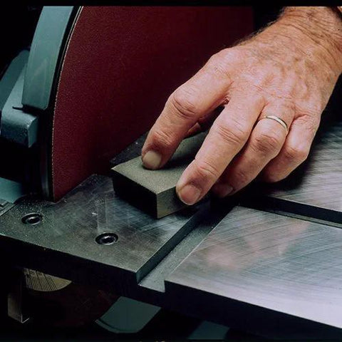 Close-up of hand using Sanding Block 3 Pack With Fine Medium Coarse Grits for shaping and rust removal on a metal surface.