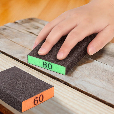 Hand using grit 80 sandpaper block on wood, with grit 60 block nearby, part of 8 Pack Sandpaper Blocks With Grits 60 80 120 220 Washable Reusable Sponges